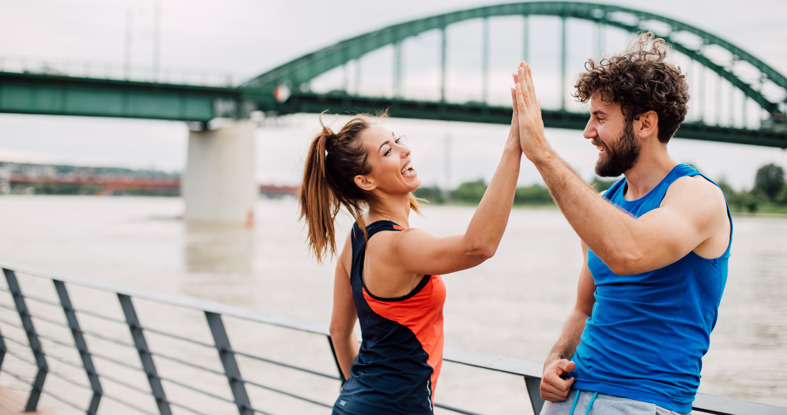 Couple smiling and high-fiving outdoors in athletic gear